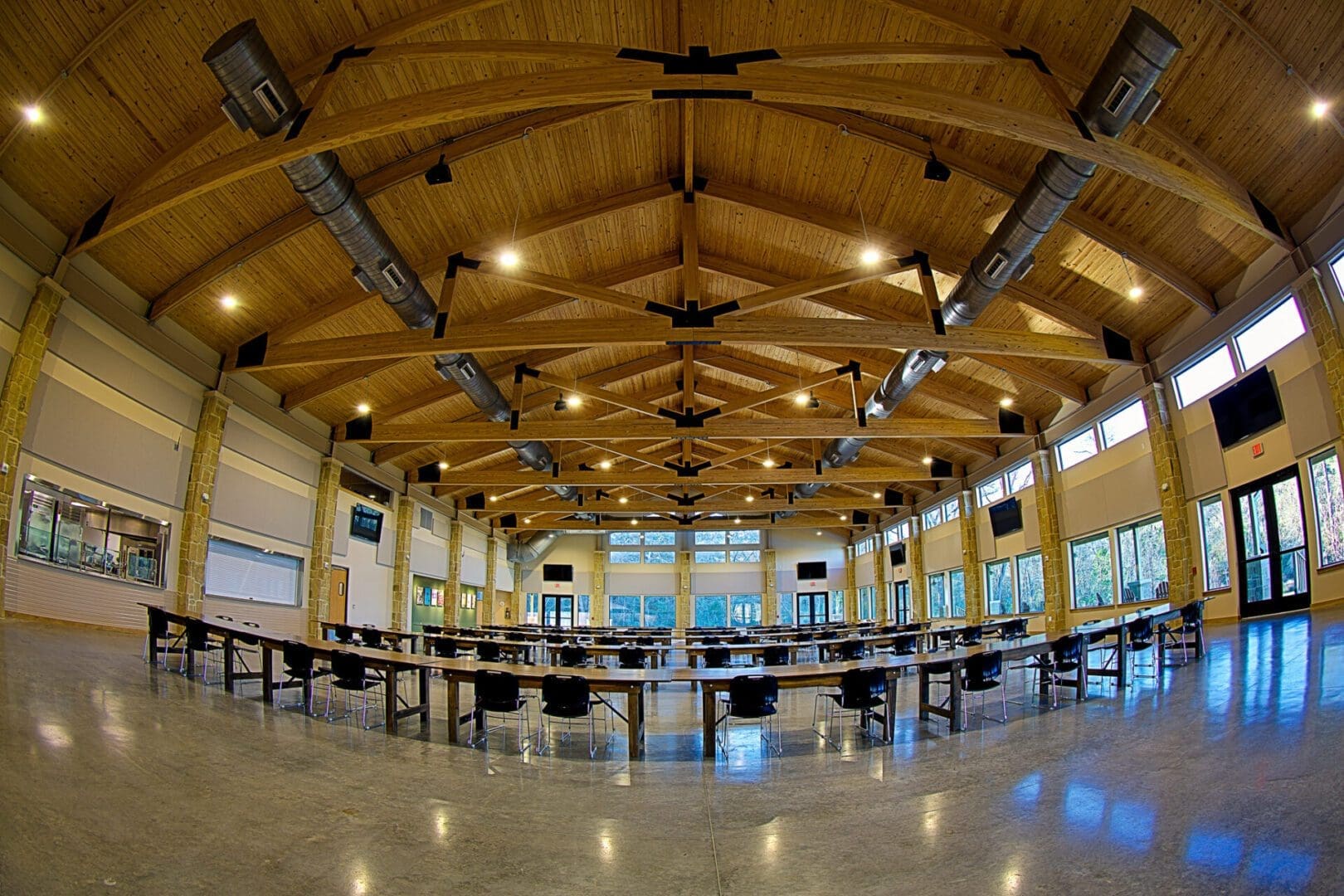 Spacious hall with wooden ceiling and tables.