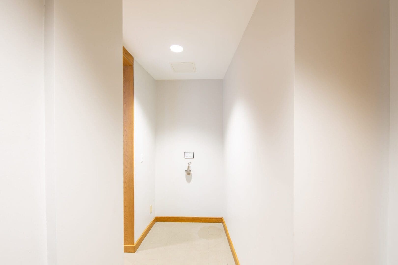 Empty white hallway with wooden trim.